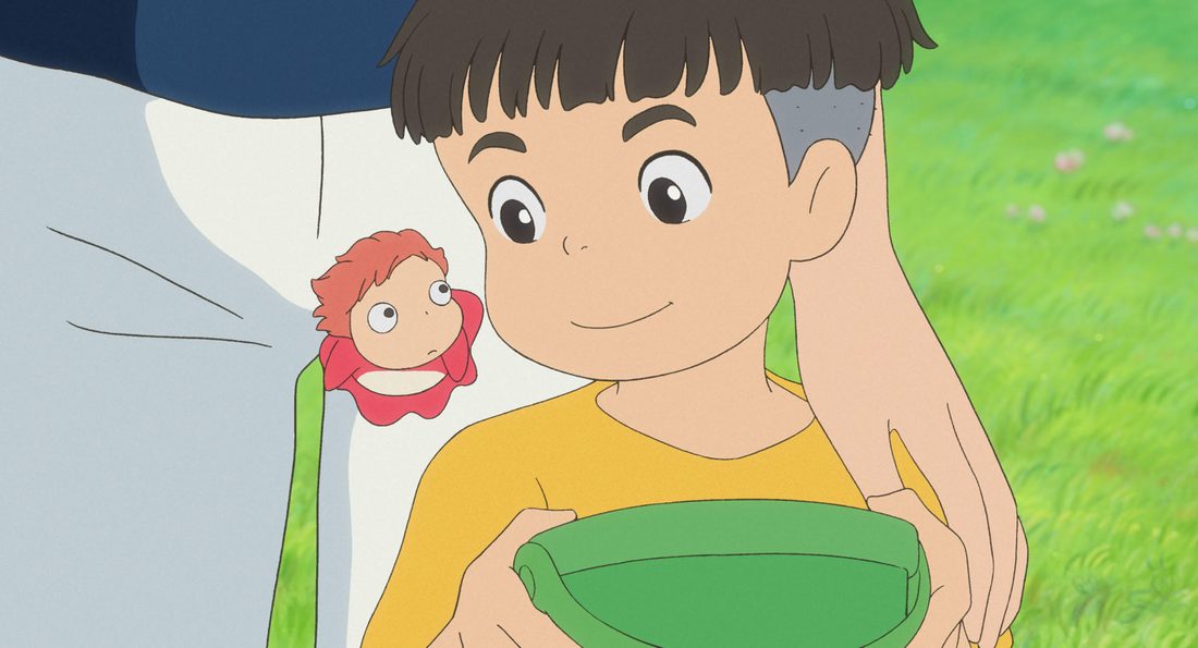 Sōsuke, en primer plano sobre la hierba, con el cubo verde y Ponyo al lado