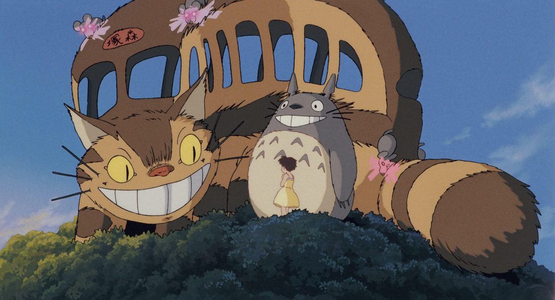 Totoro, de cuerpo entero, delante del Gatobús